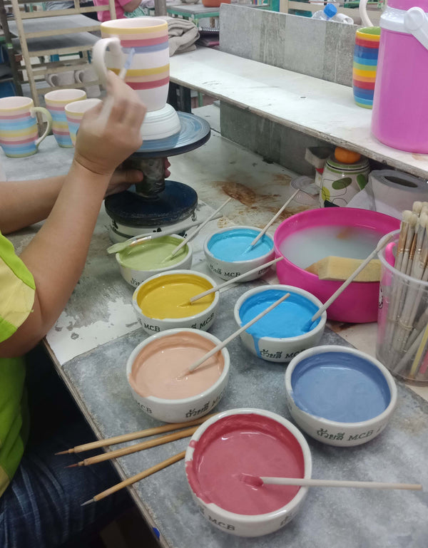 Hand painting the stripes on the rainbow striped tableware